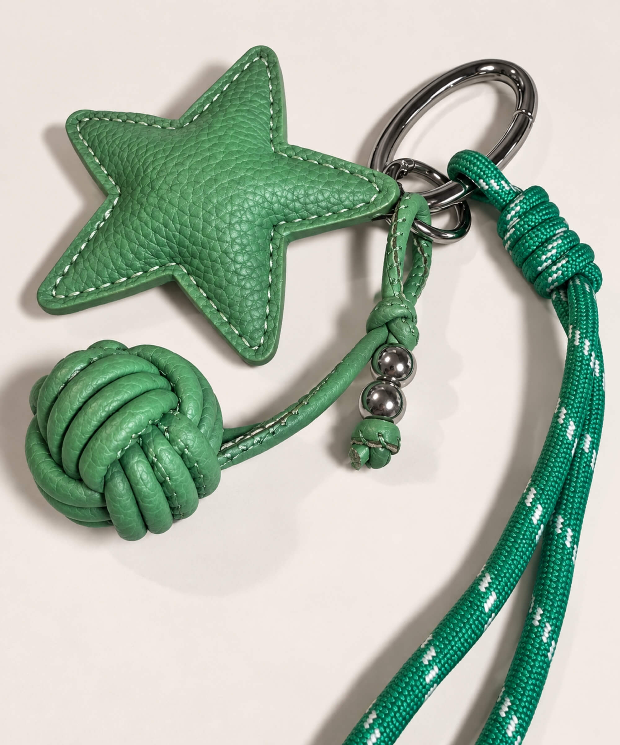 Close-up of Green star PU leather bag charm keychain with woven knot ball and rope cord